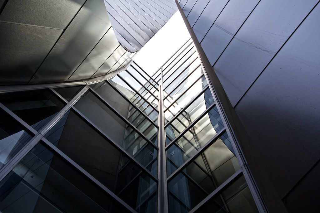 Dark glass and steel commercial facade rising against the sky