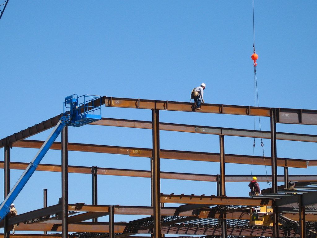Steel portal frame being erected on site with a boom lift and crew
